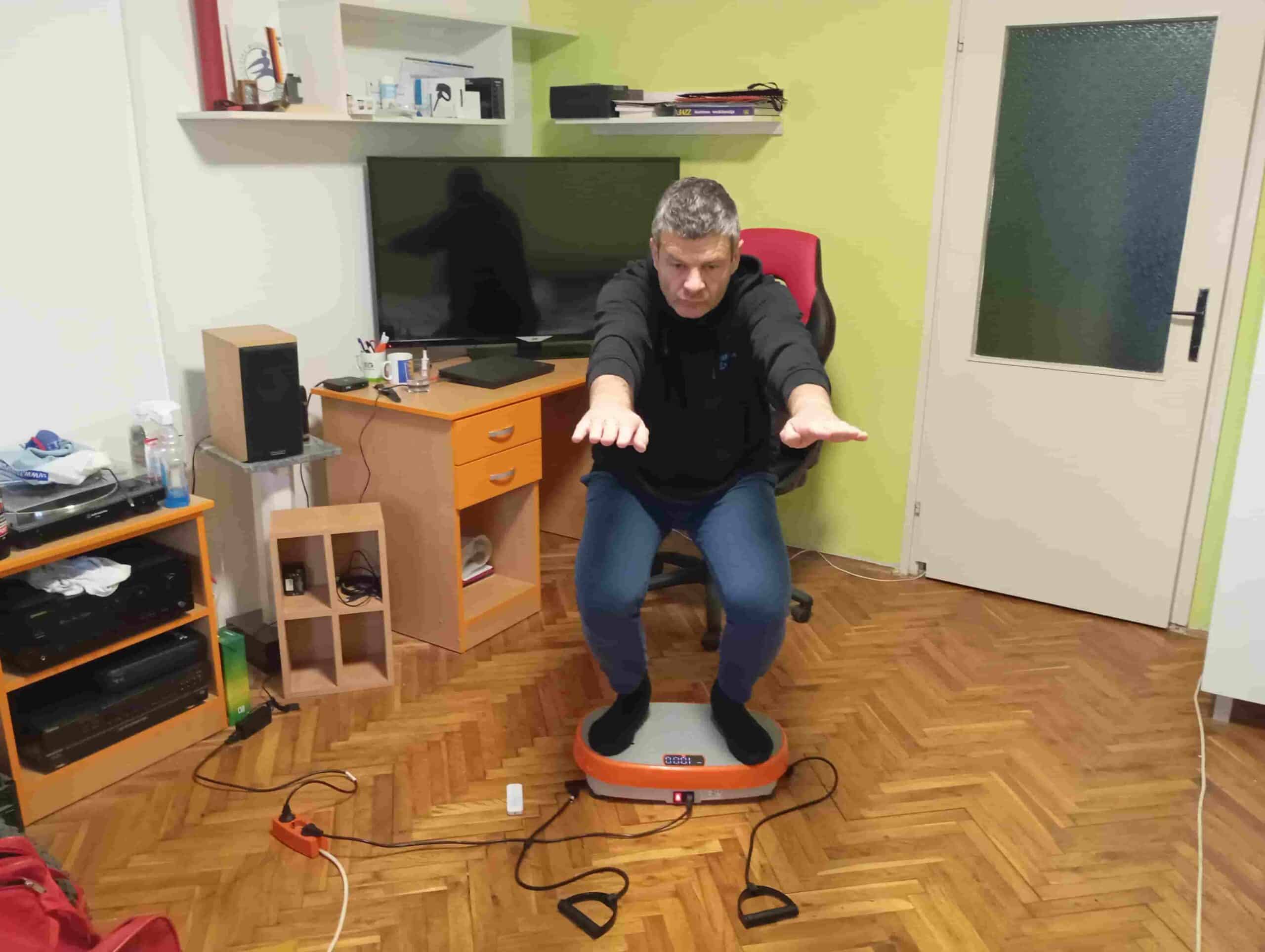 Vladimir Stanar on a vibration plate in a deeper half squat arms outstreched Vladimir Stanar on a vibration plate in a deeper half squat arms outstreched
