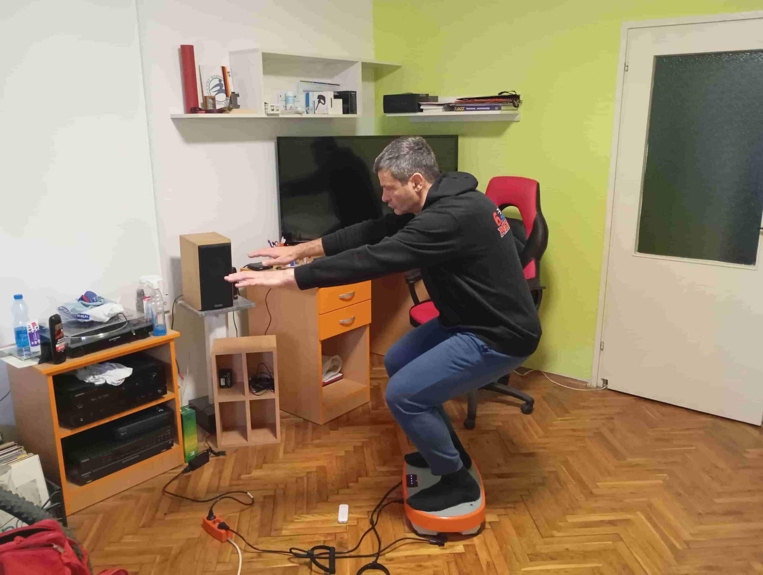 Vladimir Stanar on a vibration plate in a deeper half squat arms outstreched side view Vladimir Stanar on a vibration plate in a deeper half squat arms outstreched side view