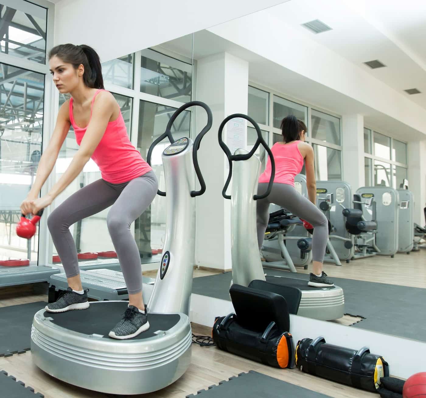 A girl working out on the  vibration plate in the gym